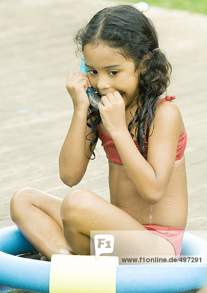 Girl sitting in ring  putting snorkel in mouth