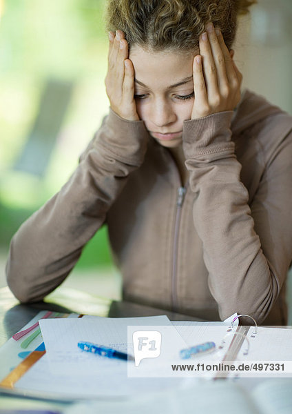 Preteen girl doing homework  holding head