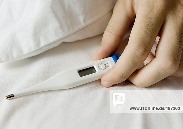 Männerhandthermometer auf dem Bett