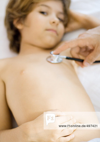 Arzt hält Stethoskop an die Brust des Jungen