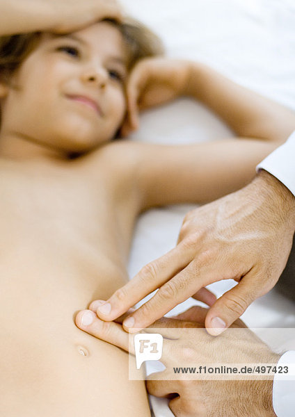 Arzt drückt Finger gegen die Jungenseite
