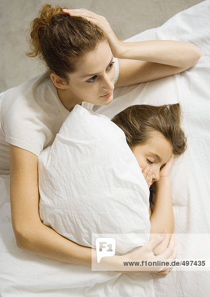 Mädchen schläft im Bett  Mutter liegt neben ihr mit Kopf auf dem Ellenbogen gestützt