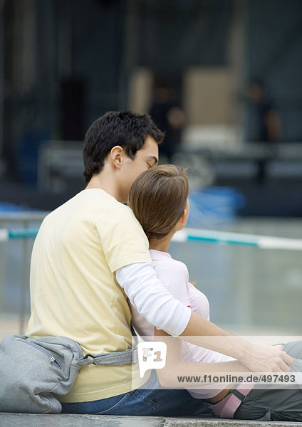 Teenager-Paar im Freien sitzend  Mädchen lehnt sich an den Jungen an
