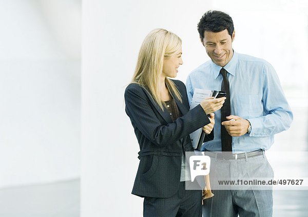 Businesswoman showing businessman cell phone