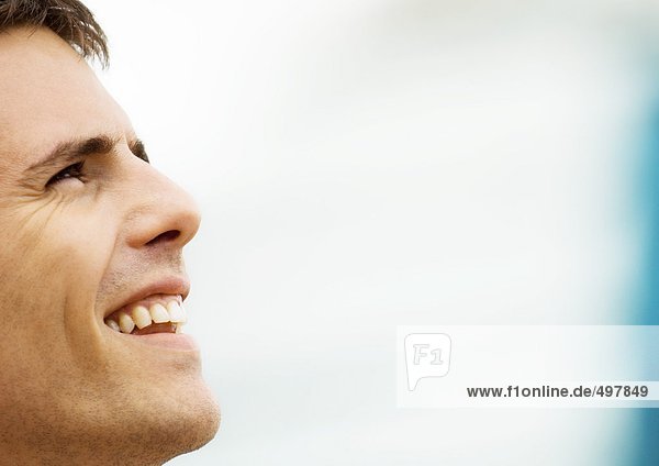 Man smiling and looking up  close-up side view of face