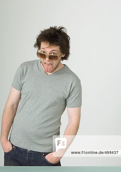 Young man wearing sunglasses  sticking out tongue
