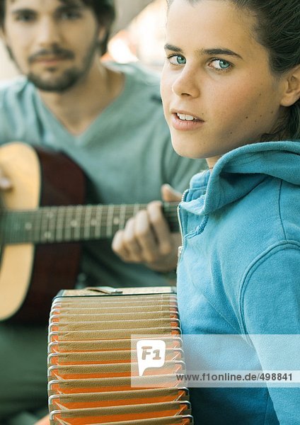 Young woman playing accordian and young man playing guitar