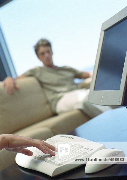 Computer  Mann auf Sofa im Hintergrund
