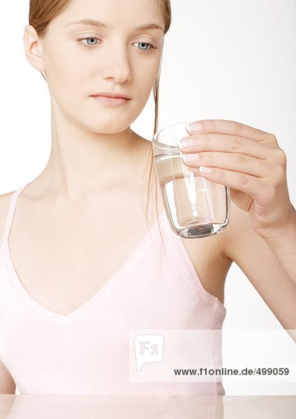 Frau schaut auf ein Glas Wasser