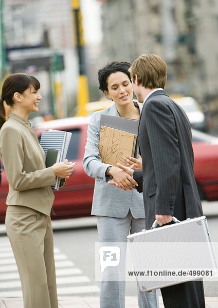Business people shaking hands on side of street