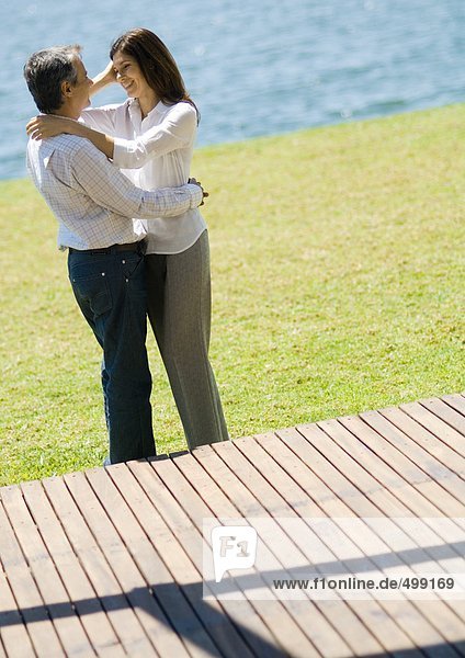 Couple standing in each other's arms near lake
