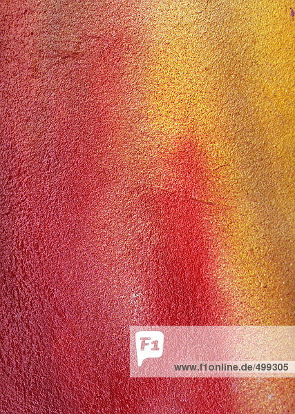 Red and yellow spray paint on concrete wall  close-up  full frame