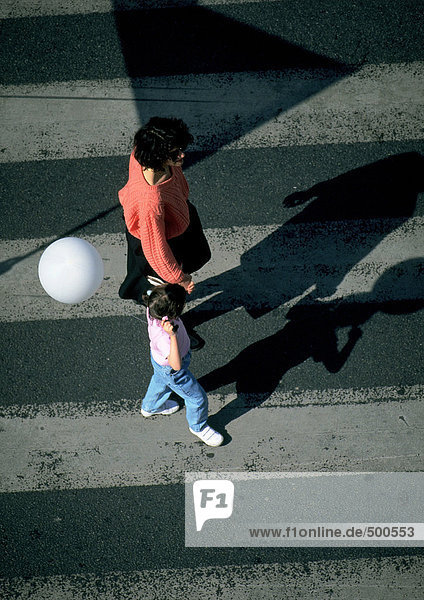Woman and young girl holding balloon  walking on crosswalk  high angle view