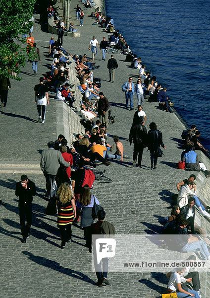 People walking and sitting by water