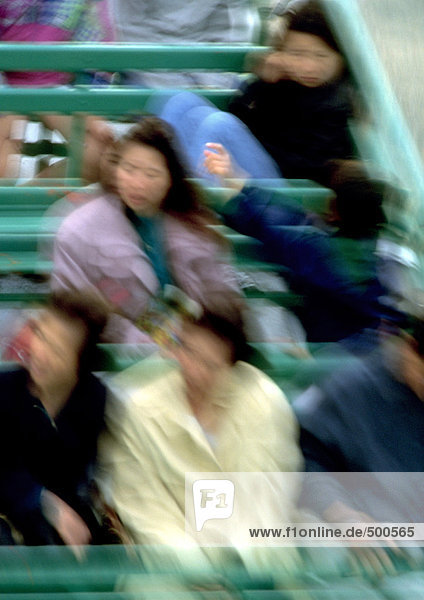 Group of people sitting in bleachers  motion  blurred.