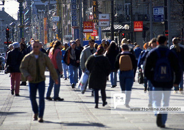 Crowd  dressed warmly  walking on sidewalk in city  blurred.