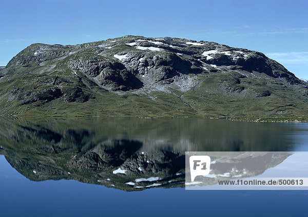 Norwegen  moosiges  schneebedecktes  felsiges Land  das sich im Meer spiegelt.