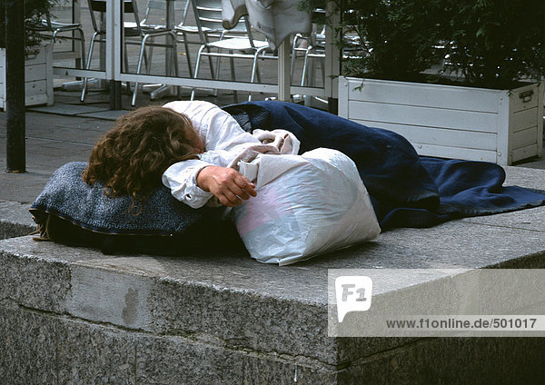 Schlafende Person auf dem Bürgersteig in der Nähe des Cafés