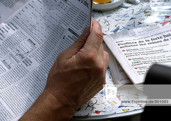 Mann liest Zeitung am Tisch  Nahaufnahme von Papier.
