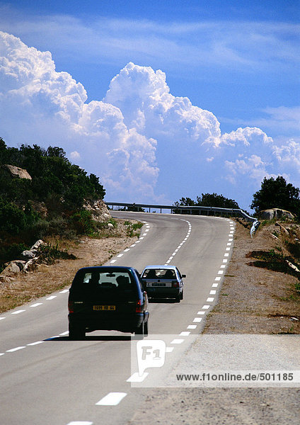 Autos auf Landstraße  Wolkenlandschaft im Hintergrund