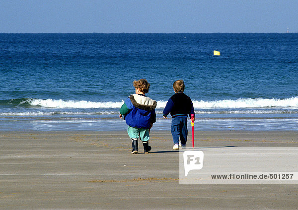 Kinder beim Spaziergang am Strand  Rückansicht