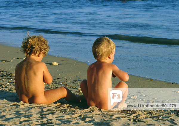 Nackte Kinder am Strand sitzend