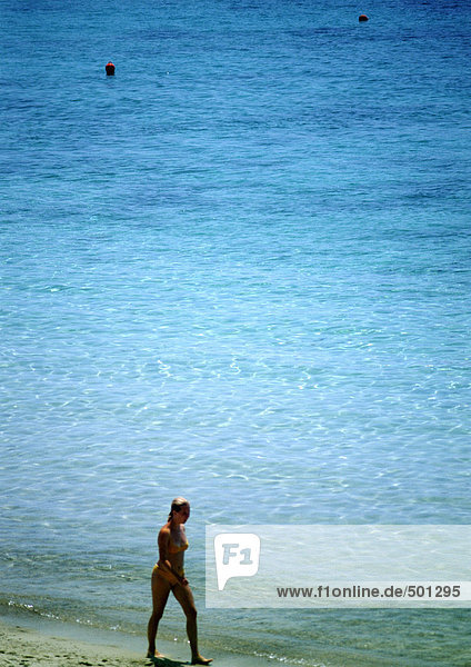 Woman walking along sea on beach  high angle view