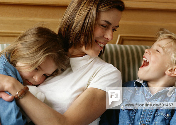 Woman holding girl in arms  looking at boy laughing