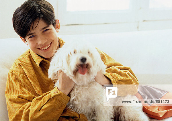 Junger Mann posiert mit einem Hund auf der Couch  Porträt.