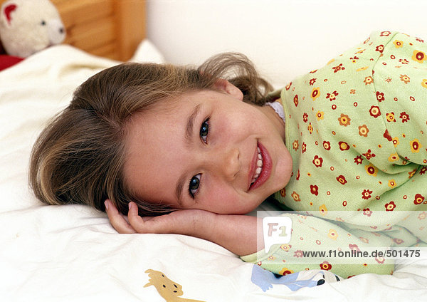 Young girl laying on bed smiling  portrait.