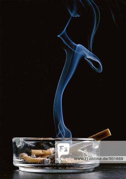 Aschenbecher mit Zigarettenkippen und Zigarettenrauchen vor schwarzem Hintergrund