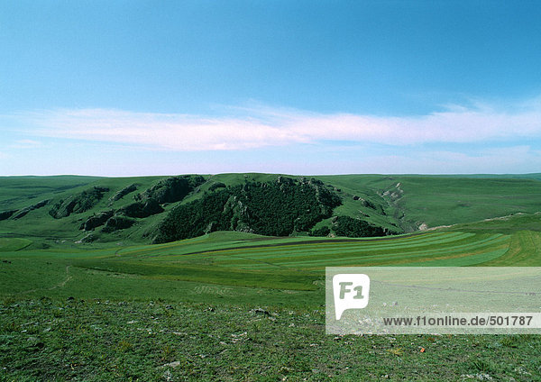 Mongolei  grasbewachsene Ebene mit grasbewachsenen Klippen