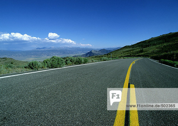 Asphalt road with yellow lines overlooking mountainous region.