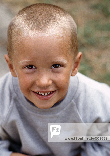 Junge mit kurzen hellen Haaren  graues Sweatshirt tragend  lächelnd  Hochwinkelansicht  Portrait