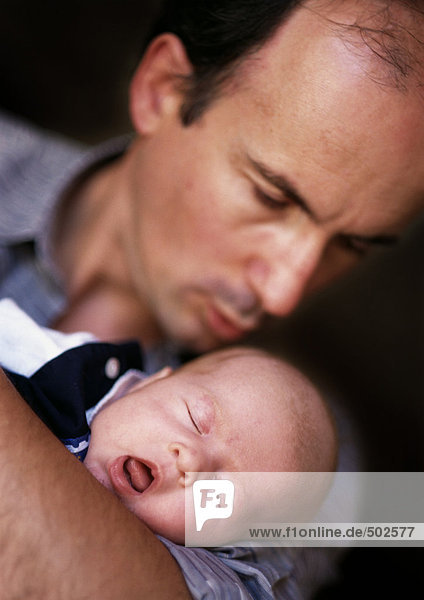 Mann hält und schaut auf das schlafende Baby  Fokus auf das Baby  Augen geschlossen und Mund offen  Nahaufnahme