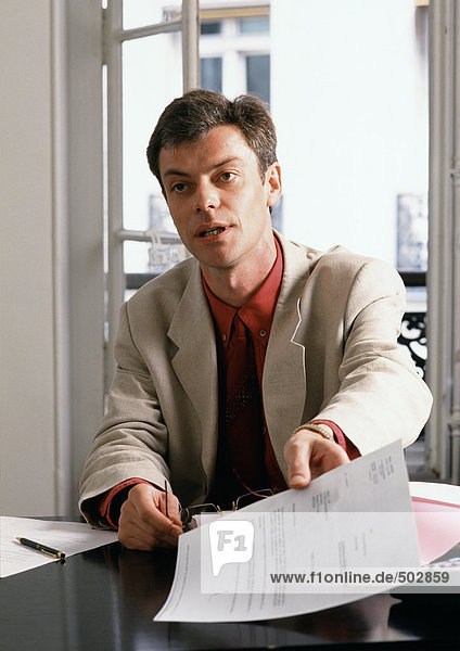 Man sitting at desk  holding document