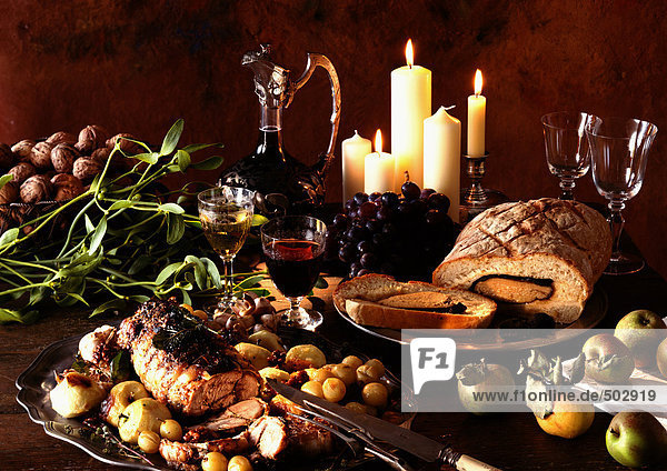 Gerichte aus Fleisch,  Obst und Gemüse,  mit Weinkaraffe und Kerzen im Hintergrund