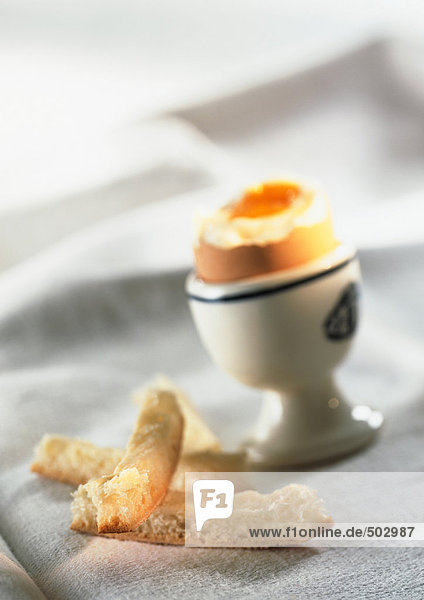 Weichgekochtes Ei im Eierbecher,  verschwommen,  mit Brotkruste