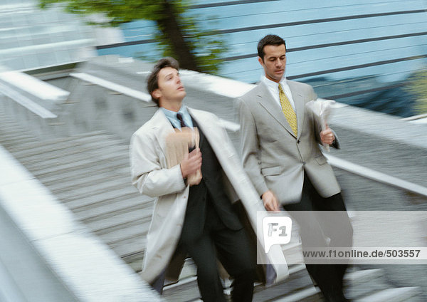 Two businessmen going down stairs side by side  blurred