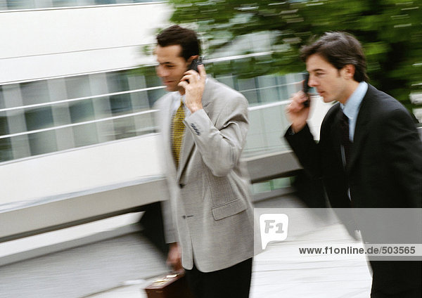 Two businessmen using cell phones outside  blurred