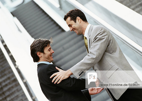 Zwei Geschäftsleute beim Händeschütteln vor der Treppe