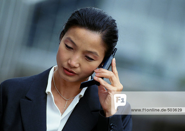 Businesswoman holding cell phone  looking down  portrait