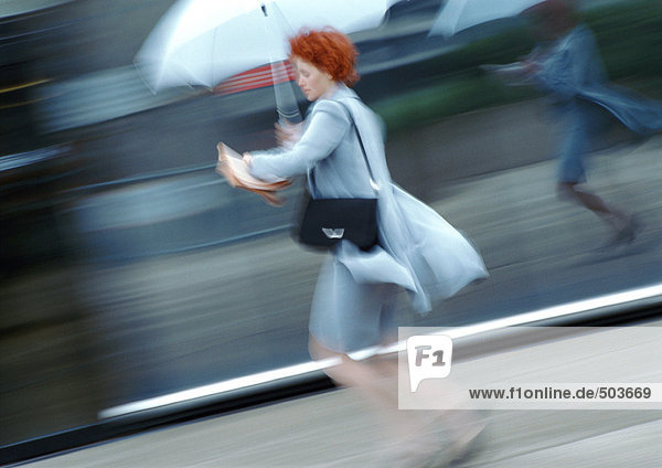 Frau auf der Straße unter dem Regenschirm gehend  verschwommen