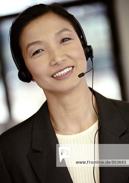 Geschäftsfrau mit Headset  Kamera lächelnd  Portrait