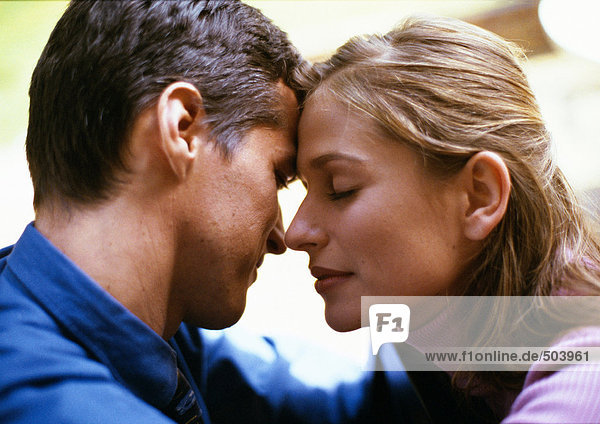 Man and woman  foreheads touching  woman's eyes closed  side view  close-up