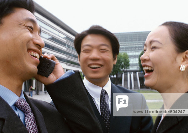 Three businesspeople laughing  one holding cell phone