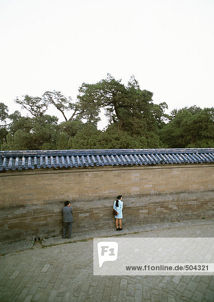 China  Peking  Tian Tan (Himmelstempel)  Echo Wall  zwei Personen  die Ohren an der Wand halten.