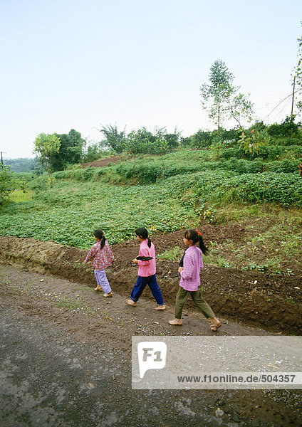 China  Autonome Region Guangxi  Kinder  die auf einem Feldweg im ländlichen Raum spazieren gehen.
