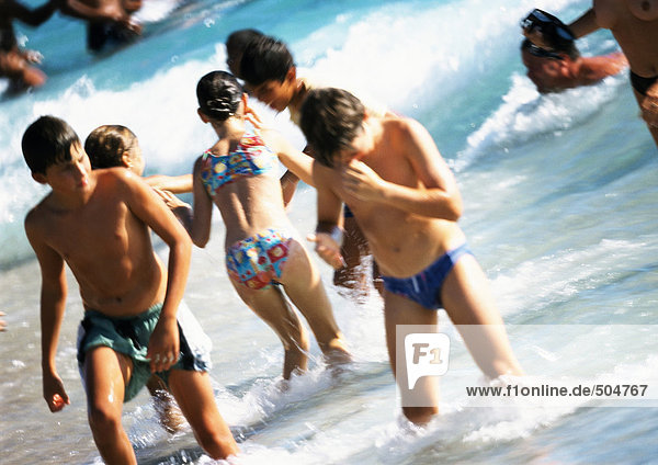 Junge Menschen stehen knietief im Wasser am Strand