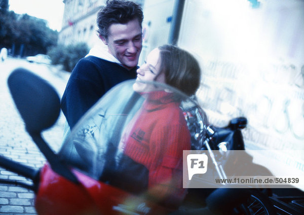 Junges Paar umarmt neben dem Roller in der Stadtstraße